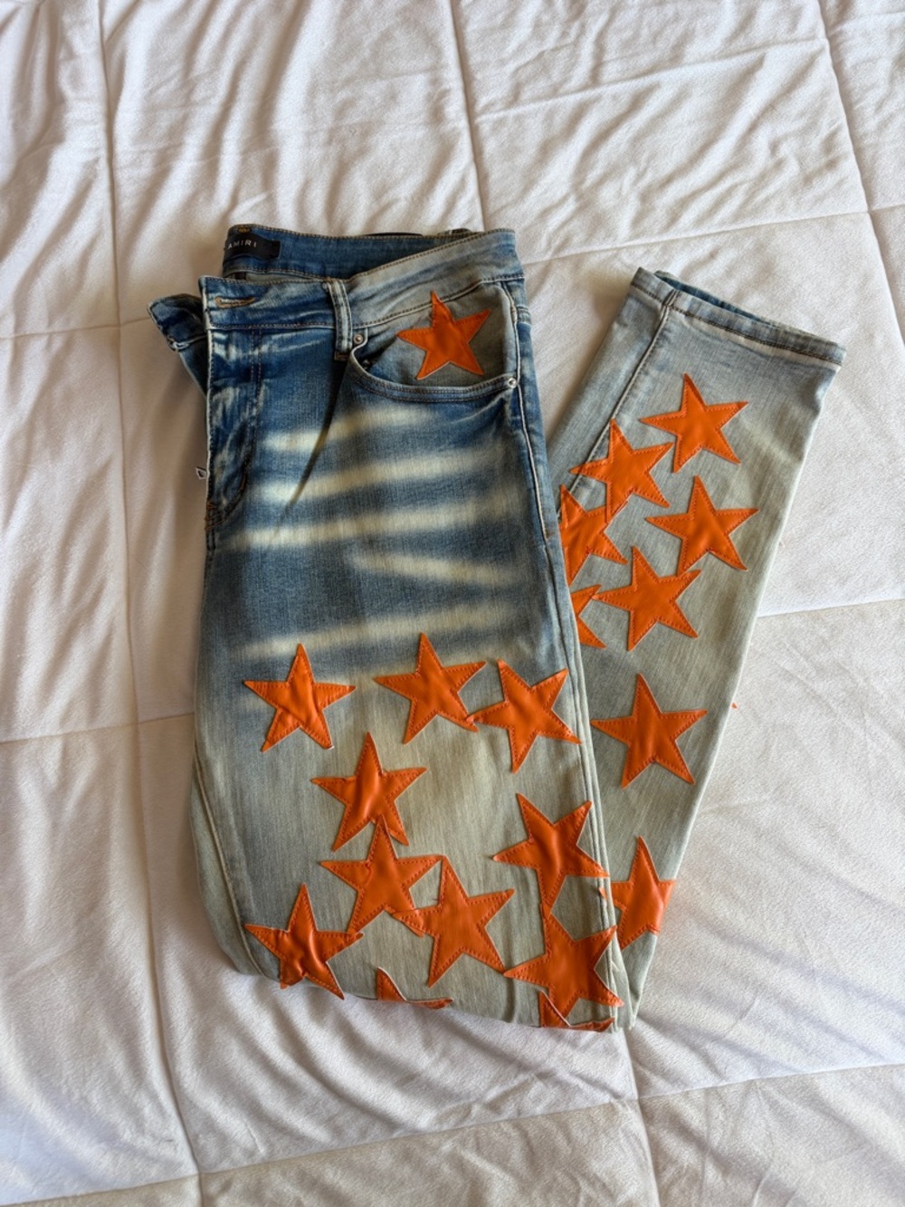 AMIRI Light Wash Skinny Jeans with Orange Star Appliqués